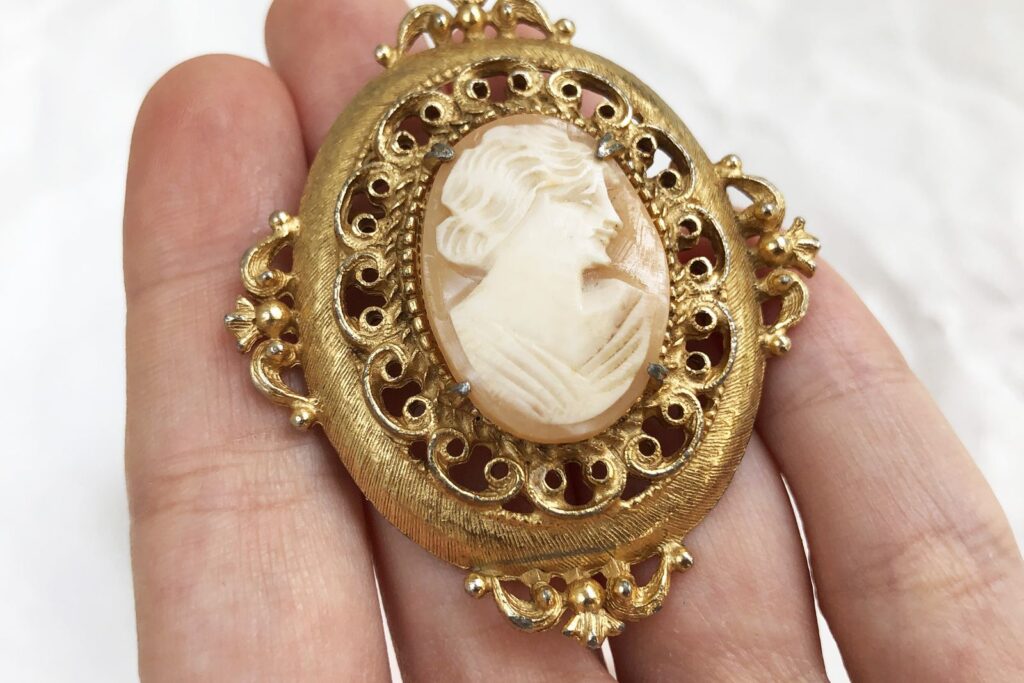 Hand holding an antique gold cameo brooch