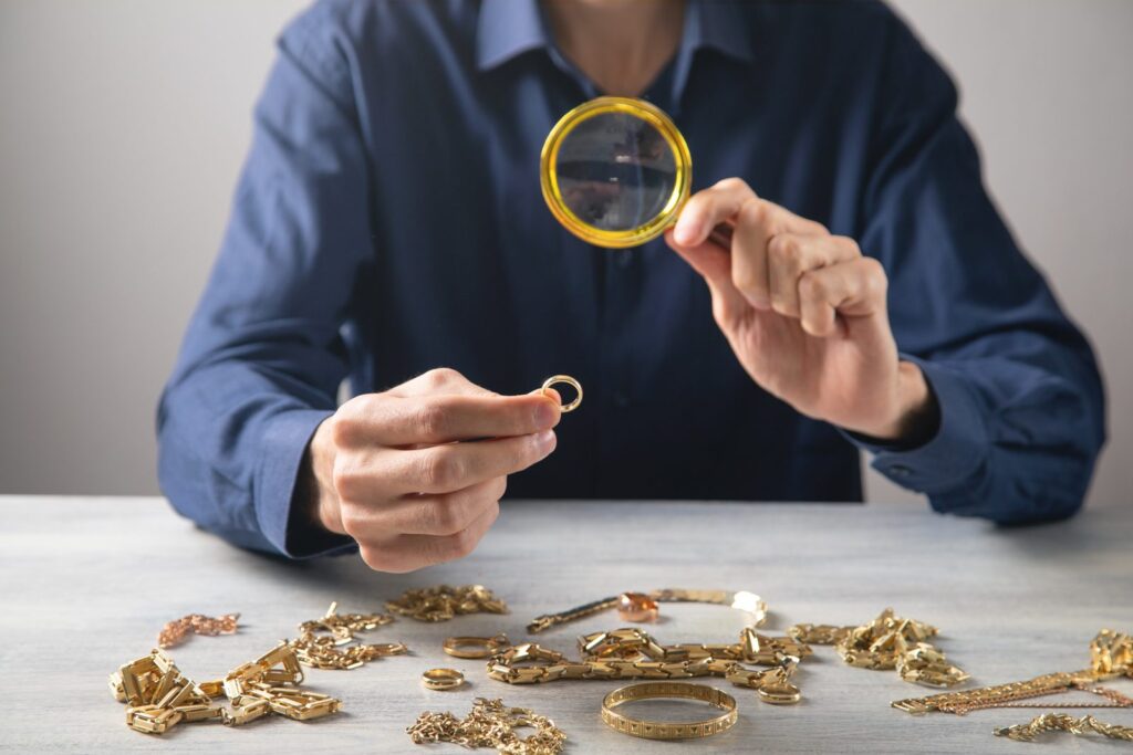 Checking the karat marks on a collection of gold jewellery with a magnifying glass