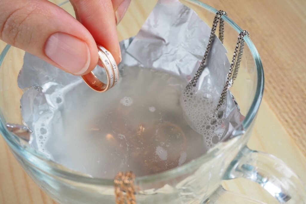 Gold and silver jewellery soaking in a glass bowl for cleaning