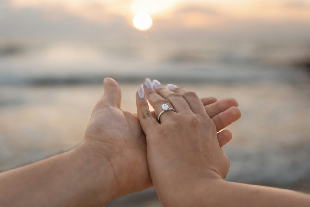 A couple’s hands with an engagement ring at sunset