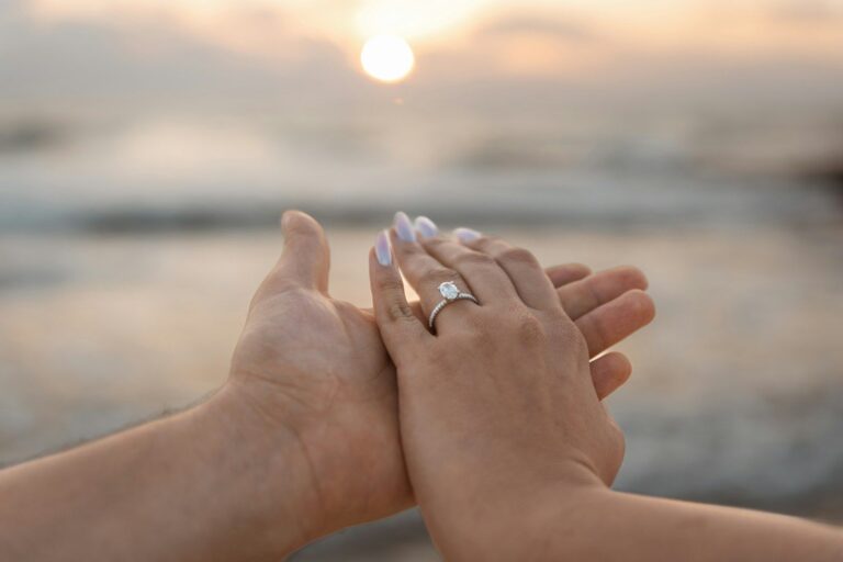 A couple’s hands with an engagement ring at sunset