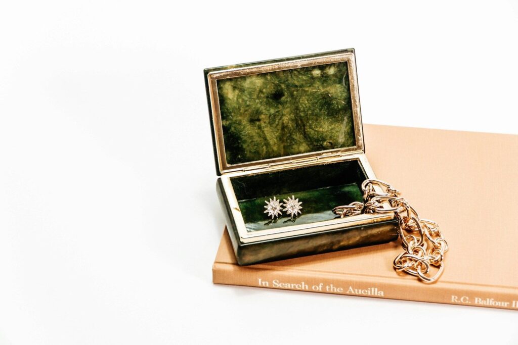 An antique jewellery box with brooches and a gold chain