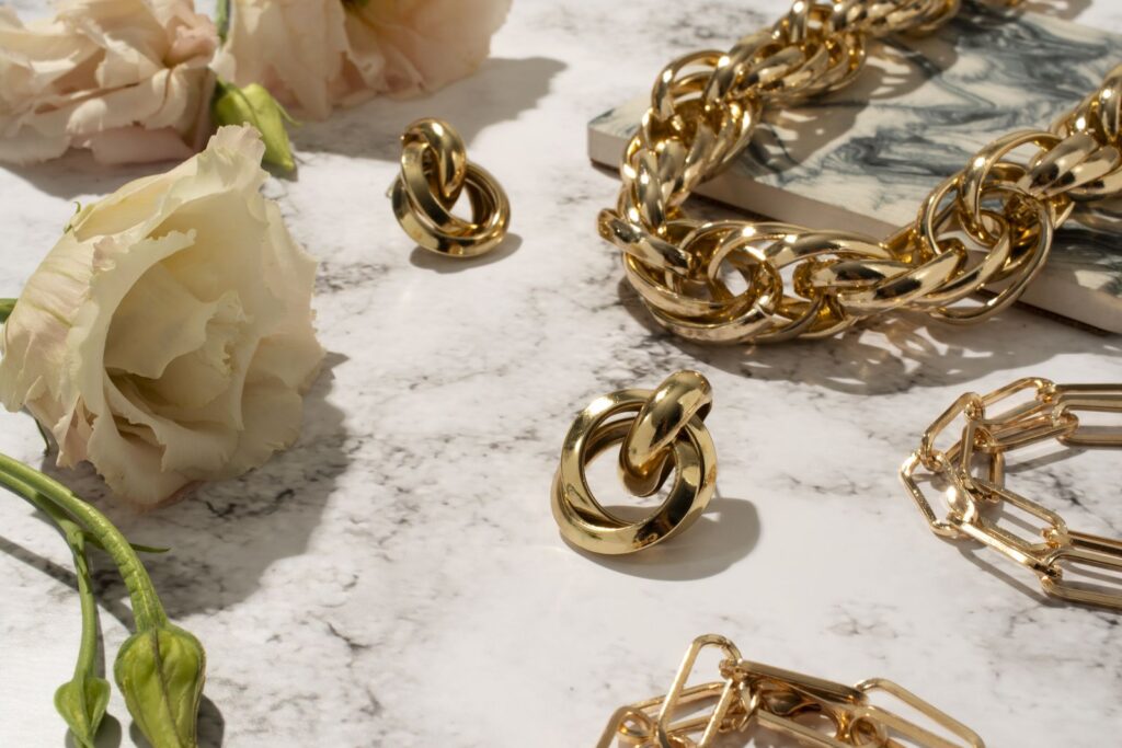 Gold chains and earrings on a marble surface