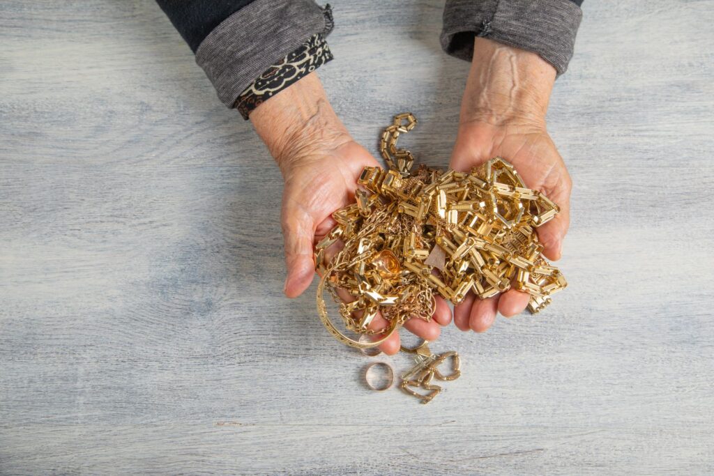 Hands holding a pile of old gold jewellery