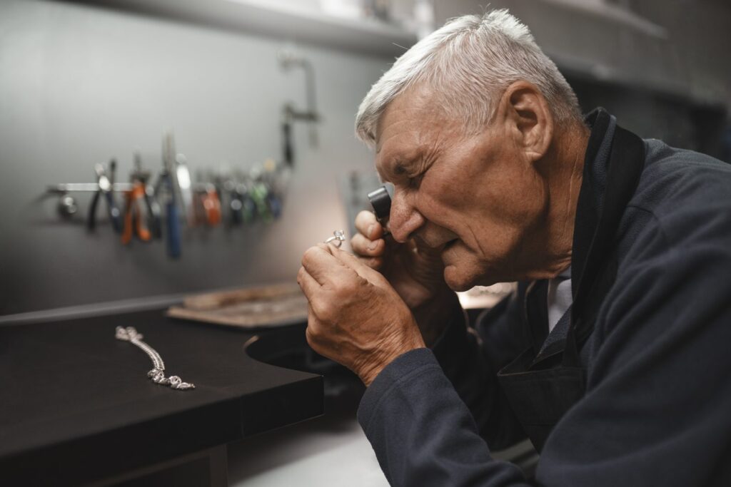 Jeweller checking a gold hallmark with a loupe in a jewellery workshop