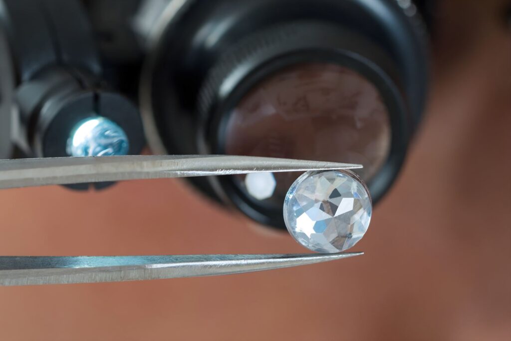 Loose diamond held in tweezers under a jeweller’s loupe