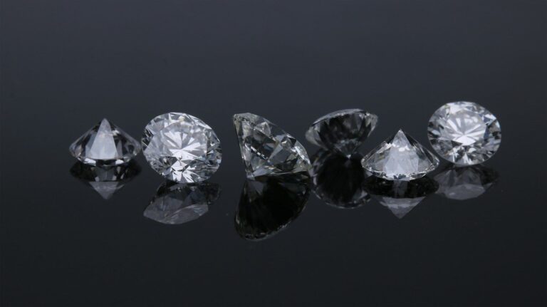 A row of loose diamonds on a reflective surface
