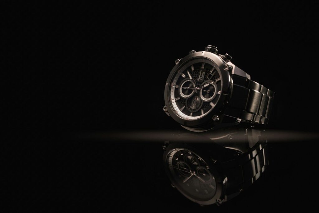 A luxury steel chronograph watch on a dark surface