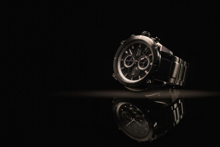 A luxury steel chronograph watch on a dark surface