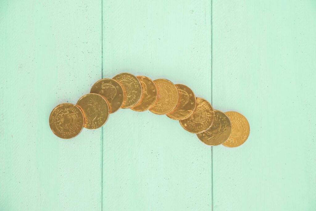Row of small gold coins on a mint green surface