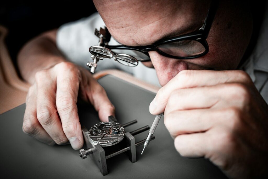 Watchmaker using a precision tool on a movement